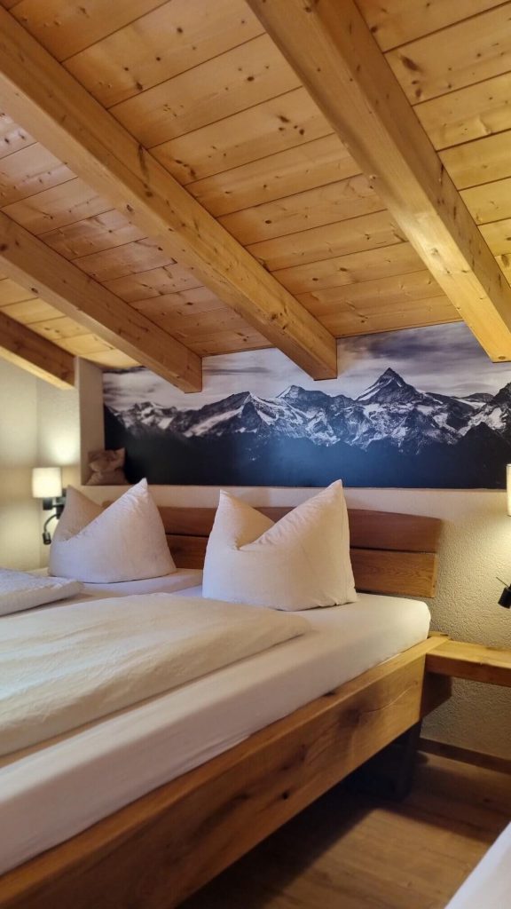 Gemütliches Schlafzimmer mit Holzdecke und Blick auf Bergmotiv im Appartement Wälderhof Kaprun.