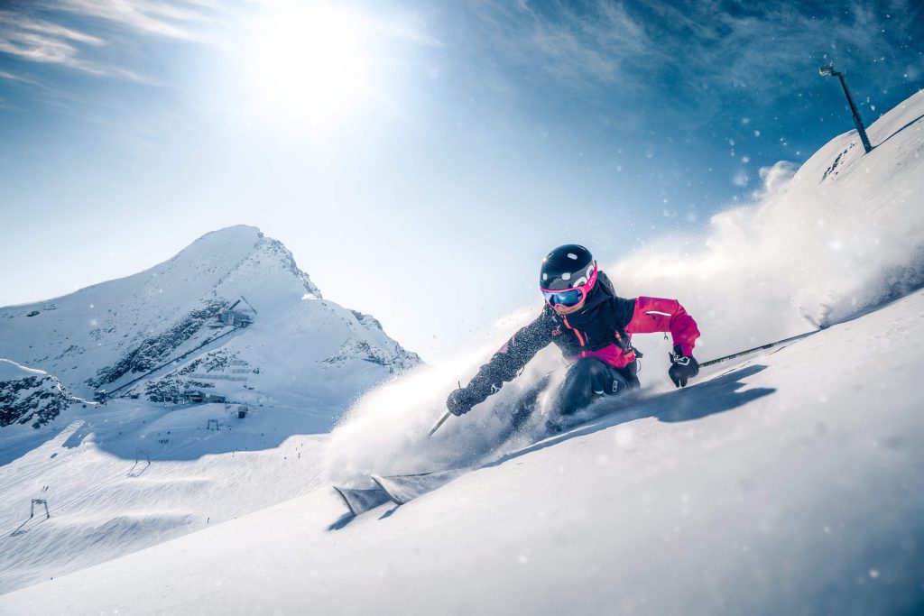 Skifahrer genießt Pulverschnee am Kitzsteinhorn bei strahlendem Sonnenschein.