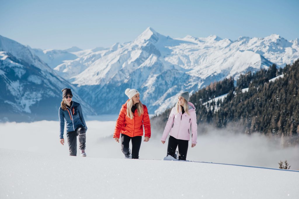 Drei Frauen wandern im Schnee mit Blick auf die Berge in der Region Kaprun.